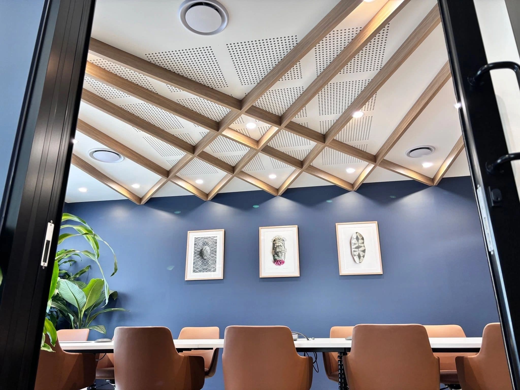 Boardroom with perforated acoustic plasterboard ceiling between timber-look battens