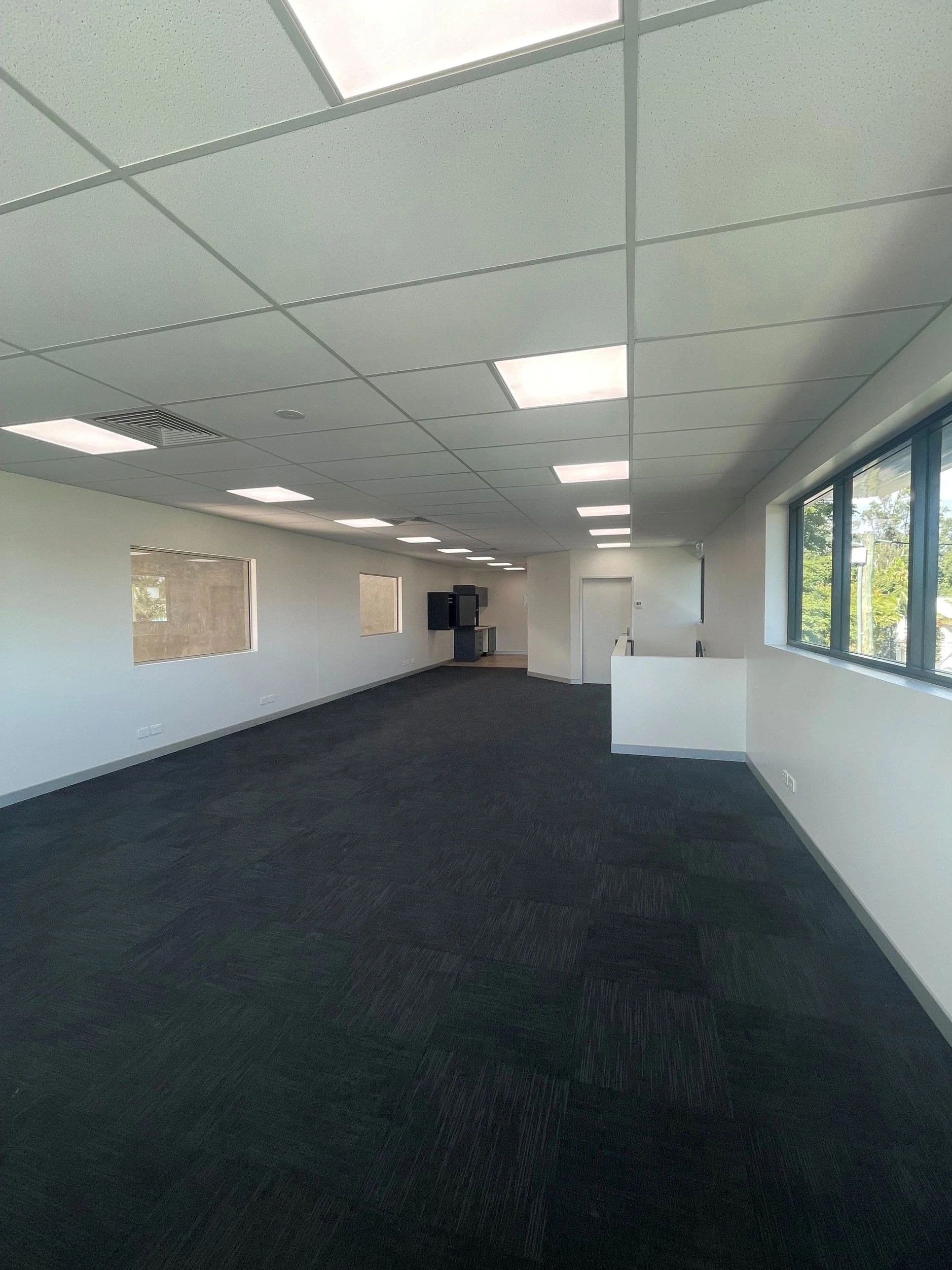 Open-plan office with an exposed grid suspended ceiling and recessed LED panels
