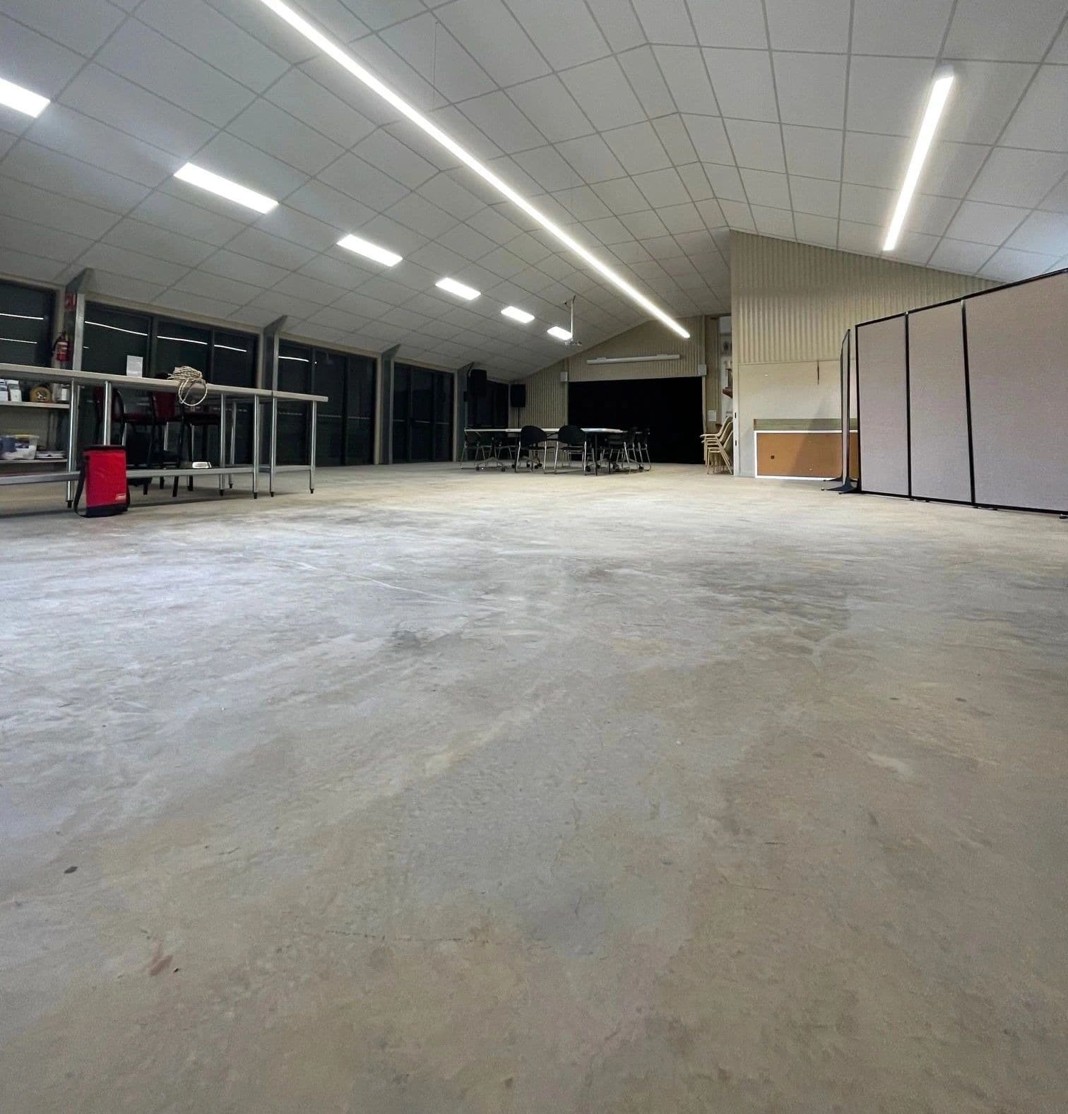 Large open commercial space with a suspended tile ceiling and linear lighting